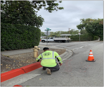 Crew worker painting new red paint on a street curb